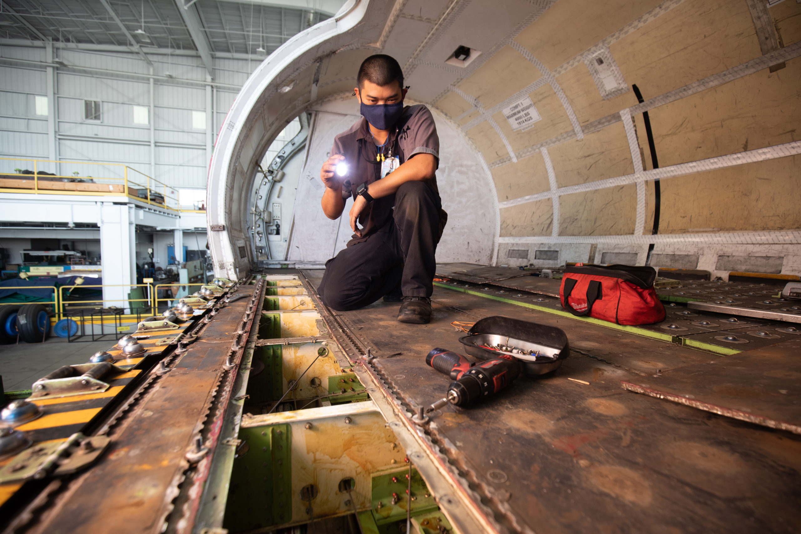 Photo of an airline mechanic with a flashlight inspecting a plane.